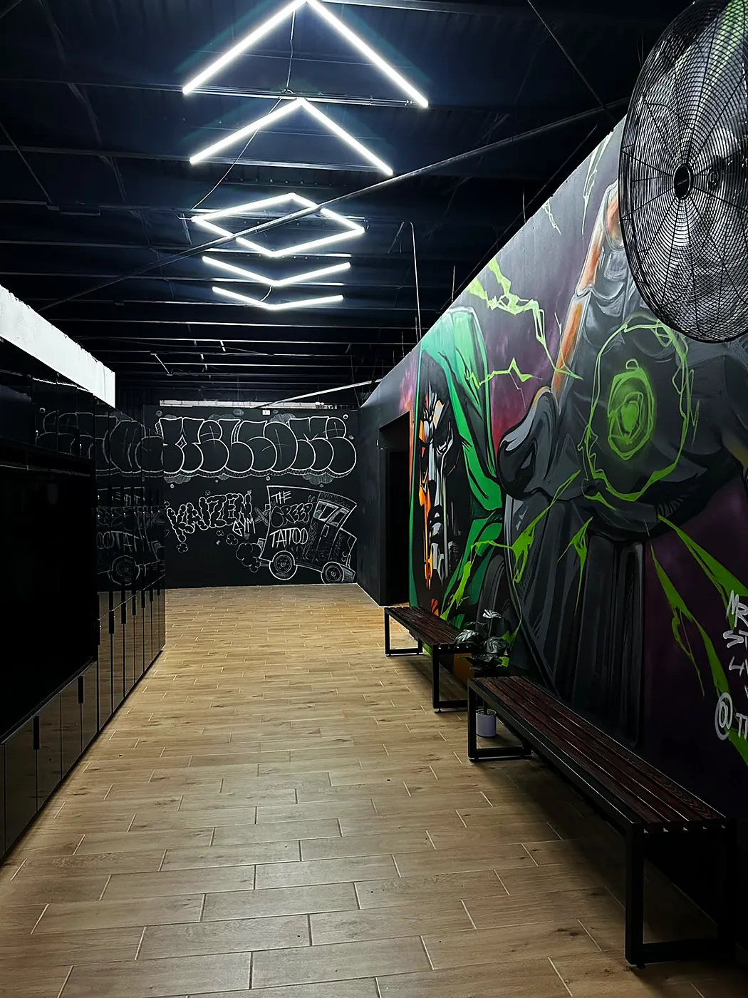 Pasillo de lockers con banca, frente al mural de Doctor Doom